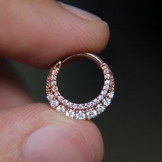 a close up of a person's hand holding a ring with diamonds on it