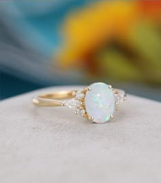 an opal and diamond ring sitting on top of a rock