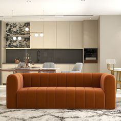 an orange couch sitting in the middle of a living room next to a dining table