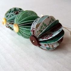 three green and white paper flowers with brown buttons on each flower, sitting on a white surface