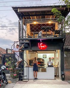 two people are standing on the stairs in front of a restaurant with an open door