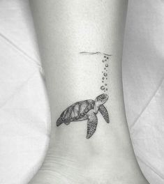 a turtle tattoo on the ankle with bubbles coming out of its shell and an ocean wave