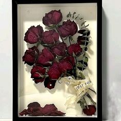 a bouquet of red roses in a shadow box