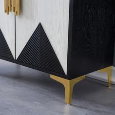 a black and white cabinet with gold accents on the bottom, along with two doors