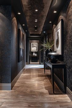 a long hallway with black walls and wood flooring is lit by recessed lights