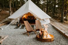 two chairs sitting in front of a fire pit with a tent on the other side