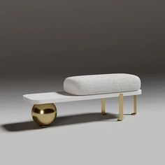 a white bench with a gold foot rest on it's side and a gray wall in the background