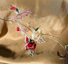 the fabric has flowers on it and is gold with pink, red and green accents