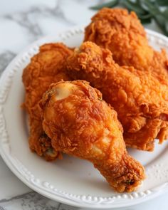 fried chicken on a white plate sitting on a marble table