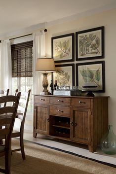 a dining room table and chairs with pictures on the wall