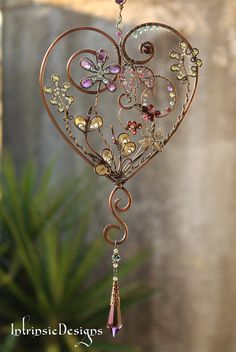 a heart shaped wind chime hanging from a wire with beads and crystals on it