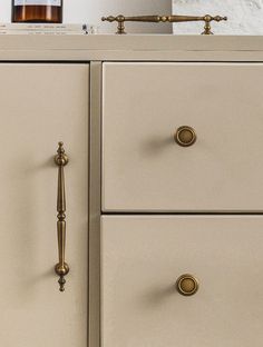 a white dresser with brass handles and knobs