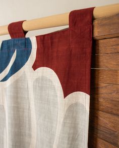 a red and white curtain hanging from a wooden rail