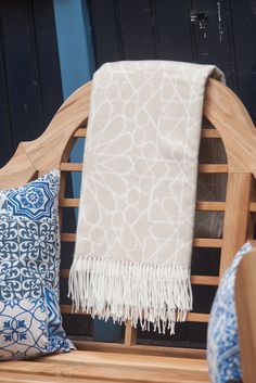 a wooden bench with two pillows and a blanket sitting on it's backrest