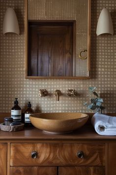 a bathroom sink sitting on top of a wooden counter next to a wall mounted mirror