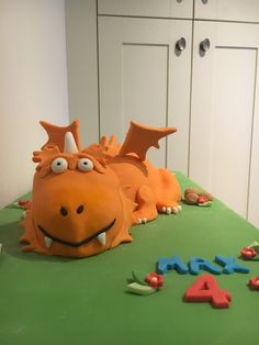 a birthday cake with an orange dragon laying on it's side and the number four spelled out