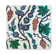 a white tile with blue and red flowers, leaves and berries on it's surface