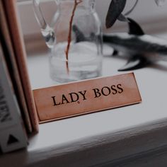 a lady boss sign sitting on top of a table next to a vase filled with flowers