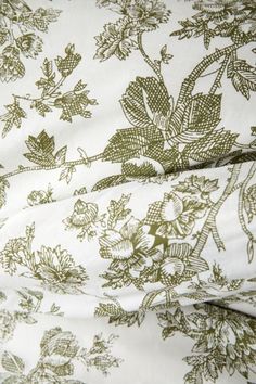 an image of a bed with green and white floral print on the sheet coverlet