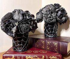 there are two vases with flowers on top of books