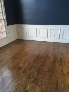 an empty room with hard wood floors and blue walls