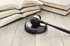 a judge's gavel sitting on top of an open book next to a stack of books