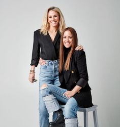 two women sitting on a stool posing for the camera with their arms around each other