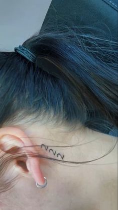 the back of a woman's head with a tattoo on her left side ear