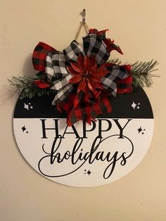 a happy holidays sign hanging from the side of a wall with red and black bows on it