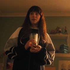 a woman holding a cup in her hands and looking at the camera with an intense look on her face