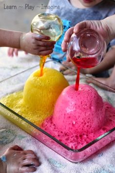 two children are playing with colored liquid in a bowl