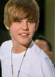 a close up of a person wearing a white shirt with a necklace on his neck