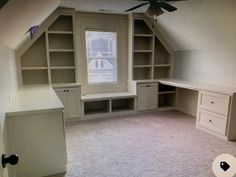 an empty room with built in bookcases and a ceiling fan