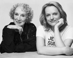 two women sitting next to each other with their arms crossed and smiling at the camera