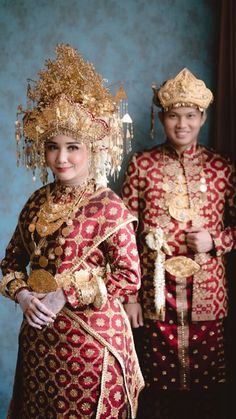 two people dressed in traditional thai garb and headdress posing for a photo