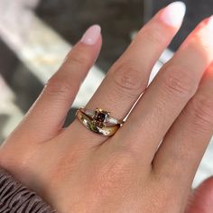 a woman's hand with a ring on it that has two different colored stones