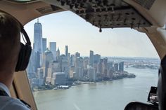 a man sitting in the cockpit of an airplane looking out over a city and river