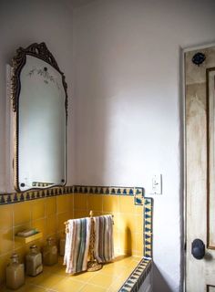 a yellow tiled bathroom with a mirror and towel rack on the counter next to it