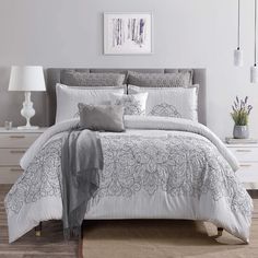 a bed with white and grey comforters in a bedroom