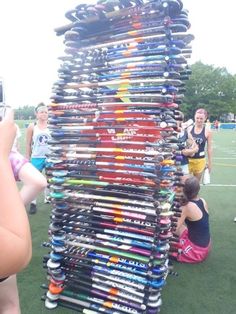 a rack full of skis and snowboards on the grass with people taking pictures