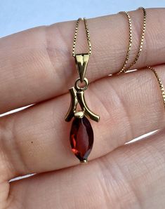 Featuring a natural marquise-shaped red garnet, the dangled pendant showcases the deep, fiery color of the stone, perfectly complemented by the warm tone of the 18k gold. Whether worn alone or layered with other necklaces,this piece is a perfect accessory for any occasion.  A matching pair of earrings as well as a matching necklace are available.  Details: - Natural Garnet, marquise shape, fine step cut, size: 10mm x 5mm - 18k Gold, solid - Pendant Length: 2,2 cm Handmade in Ouro Preto, Brazil. Red Marquise 14k Gold Jewelry, Luxury Marquise Ruby Gold Jewelry, Garnet Marquise Cut Jewelry Gift, Marquise Cut Garnet Jewelry Gift, Gold Marquise-cut Ruby Jewelry, Marquise Garnet Jewelry For Gift, Gold Ruby Marquise Cut Jewelry, Gold Marquise Cut Ruby Jewelry, Elegant Marquise Garnet Jewelry