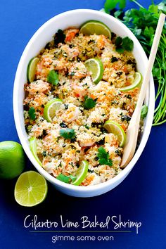 a white bowl filled with food next to limes and cilantro on a blue surface