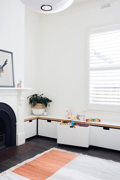 a white room with a fireplace and some toys on the floor in front of it