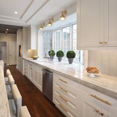 a kitchen with white cabinets and marble counter tops