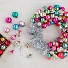 a wreath made out of christmas balls and tinsel next to some other holiday decorations