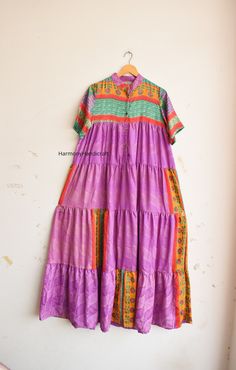 a purple dress hanging on a wall next to a wooden hanger with an orange and green stripe