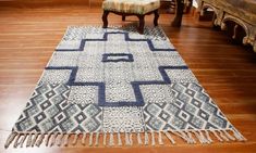 a blue and white rug on the floor in a room with wooden floors, two chairs and a bench