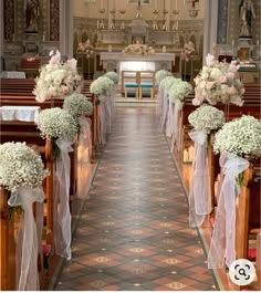 the aisle is decorated with white flowers and ribbons