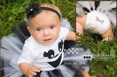 a baby girl wearing a white shirt and black tutu skirt with an owl on it