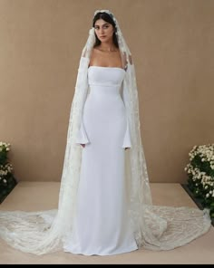 a woman in a white wedding gown with a long veil on her head and shoulders